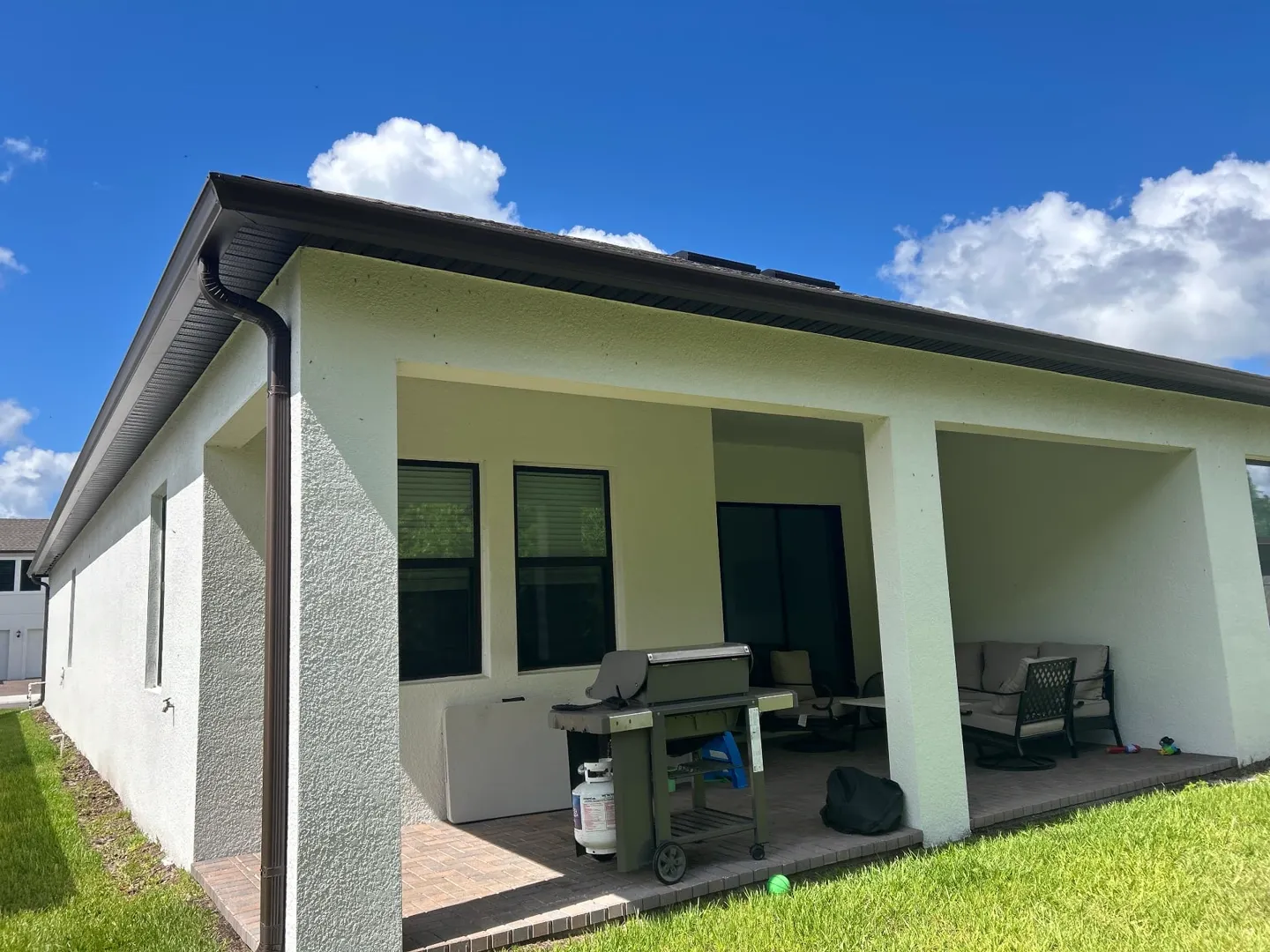 6-inch Musket Brown seamless K-style gutters and a brown downspout at the back corner of a Brandon FL home