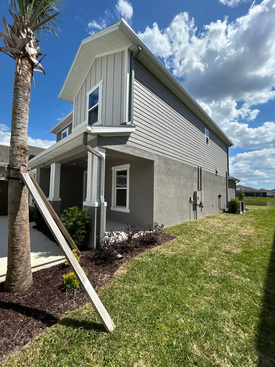 Color-matched gray downspouts and elbows running down the side of a two-story Florida home with gray siding