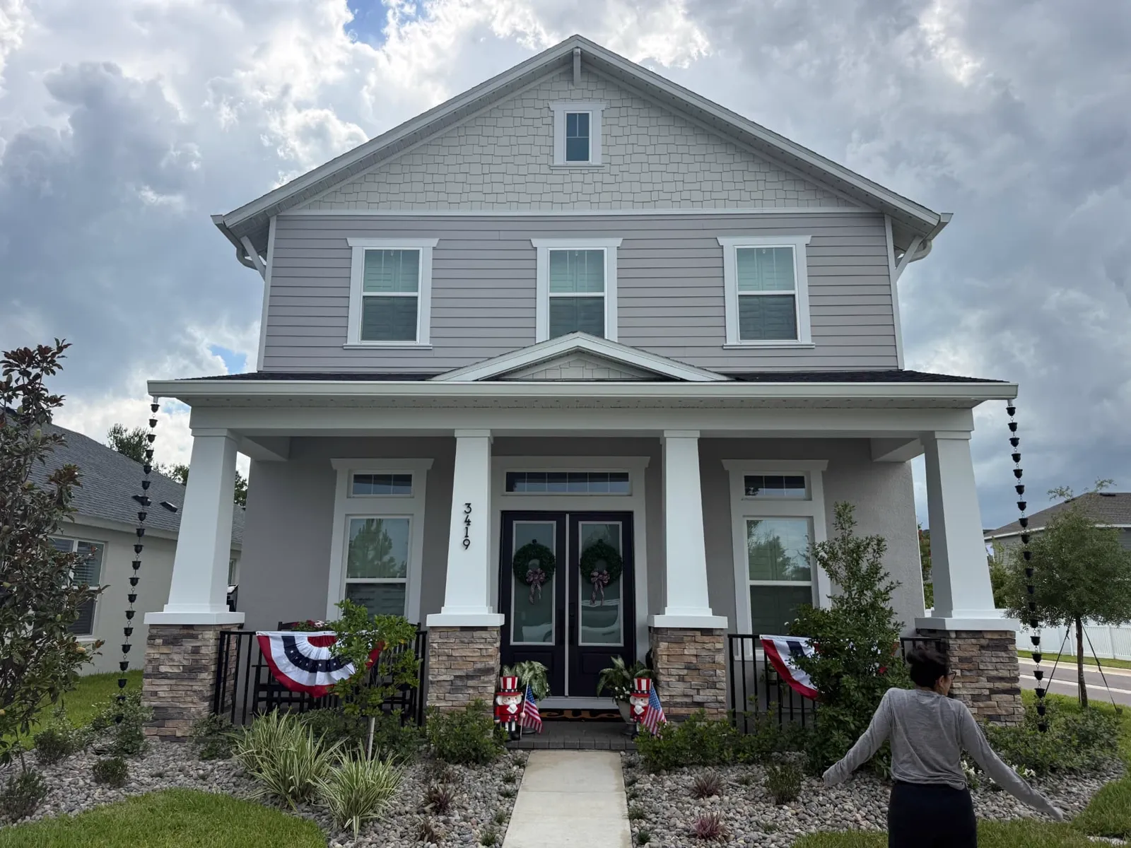 Front elevation of a home with rain chains at both ends of the covered porch instead of downspouts