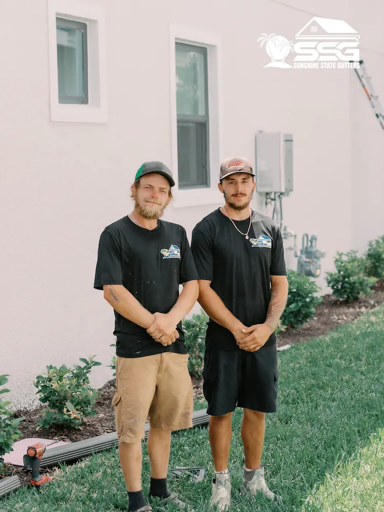 Two Sunshine State Gutters installers standing outside a home during a gutter installation project in Tampa, Florida.