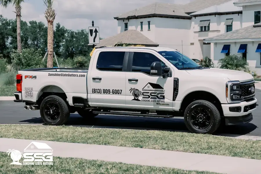 Sunshine State Gutters truck and enclosed trailer parked outside a Florida home during an installation