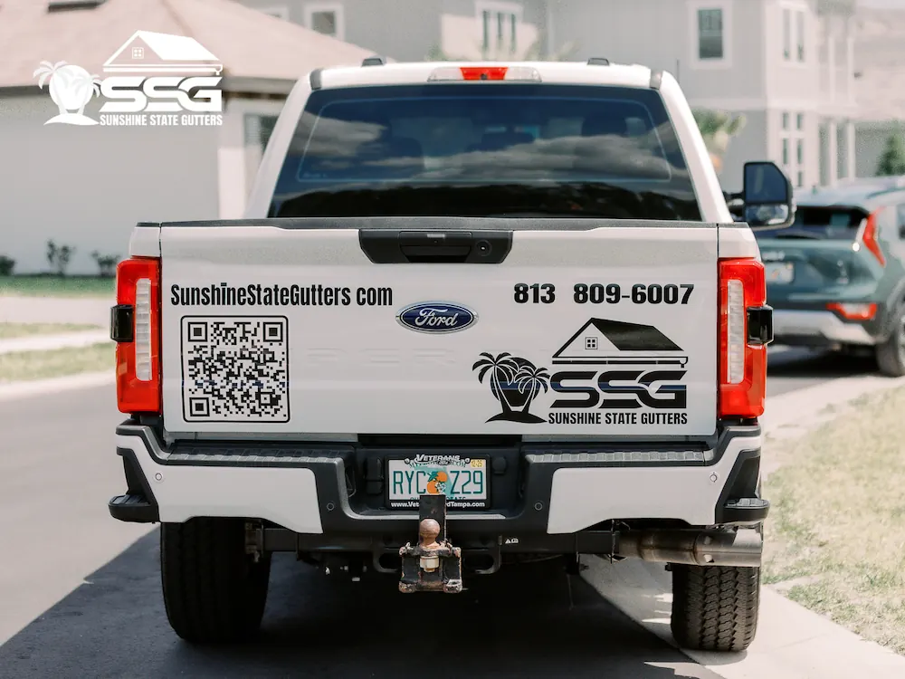 Sunshine State Gutters branded work truck with company logo, QR code, website, and phone number displayed on the tailgate in a Florida neighborhood.