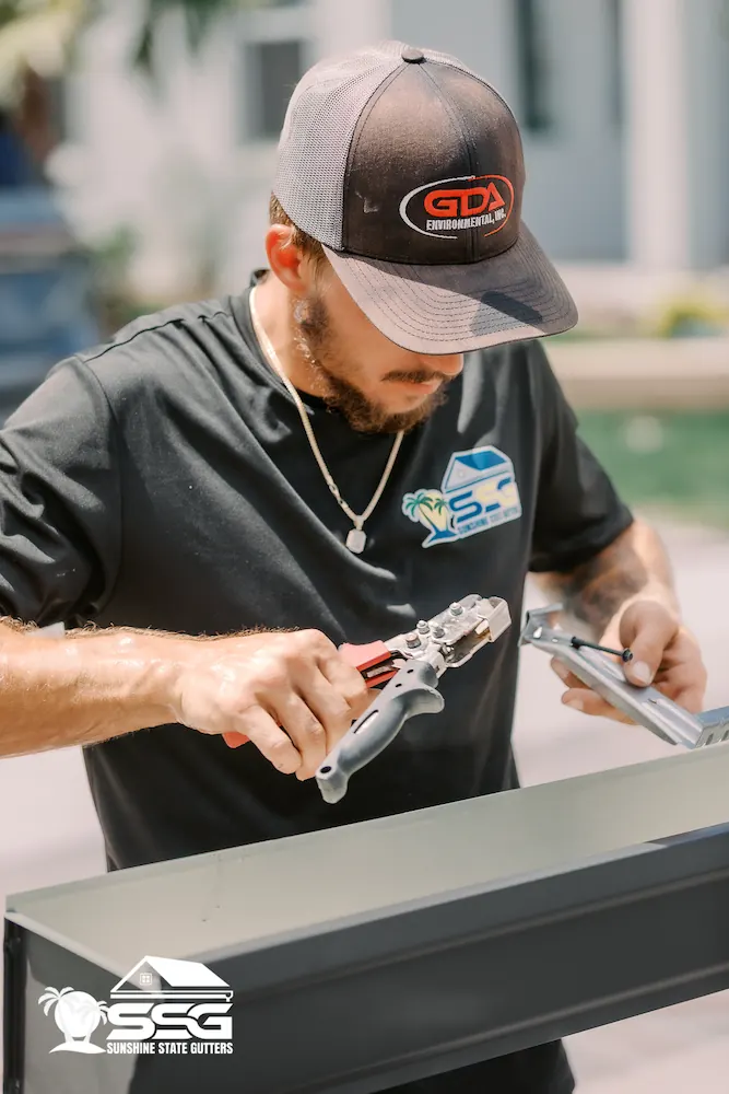 Sunshine State Gutters installer cutting and preparing gutter sections during a residential installation in Tampa, Florida.